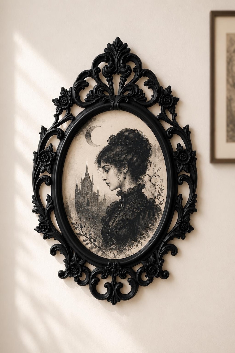 K&ouml;nnte beinhalten: Ein ovaler Wandspiegel mit einem schwarzen, verzierten Rahmen mit Blumenornamenten. Im Inneren des Rahmens befindet sich eine schwarz-wei&szlig;e Illustration einer Person mit Hochsteckfrisur vor einem Schloss unter einer Mondsichel.