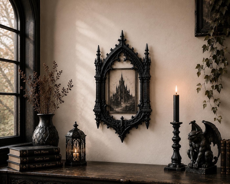 May include: A black ornate gothic-style wall frame featuring a pointed arch design, enclosing a rectangular print of a tall castle. The frame is detailed with vertical columns and pointed finials, mounted on a wall above a dark wooden surface.