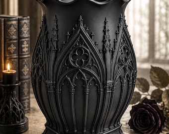 Könnte beinhalten: Eine mattschwarze Vase mit detaillierten, erhabenen architektonischen Verzierungen, die an Kathedralenbögen und Vierpassmotive erinnern. Das Gefäß hat einen breiten, gewellten Rand, einen konischen Körper und einen sechseckigen Sockel.