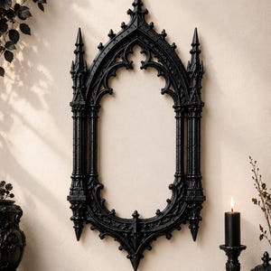 May include: A black wall mirror featuring an intricate frame with pointed arches, spires, and decorative finials reminiscent of cathedral architecture. The frame has a matte finish and a symmetrical, elongated oval shape with detailed carvings.