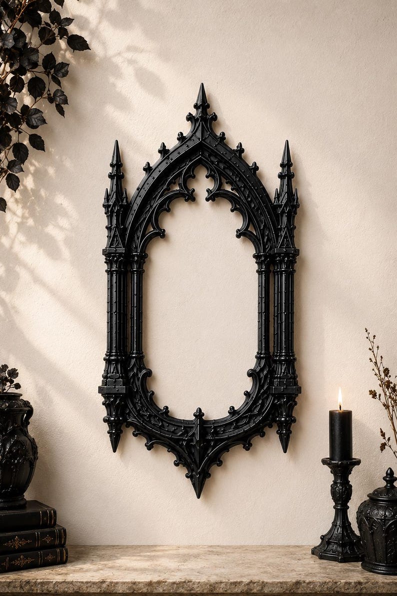 May include: A black wall mirror featuring an intricate frame with pointed arches, spires, and decorative finials reminiscent of cathedral architecture. The frame has a matte finish and a symmetrical, elongated oval shape with detailed carvings.