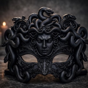 May include: A black Medusa mask with intricate details, including snakes and a stern facial expression. The mask is made of a dark material and features ornate carvings, perfect for costume parties or theatrical performances.