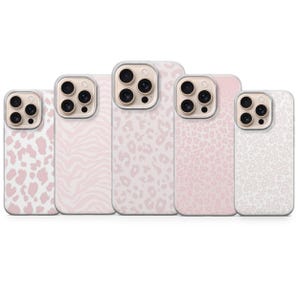 May include: Five phone cases with various pink and white animal print designs, including leopard and zebra patterns. The cases have a clear border around the camera and are arranged in a row.
