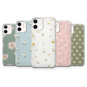 Pode incluir: Cinco capas de telemóvel com padrões de margaridas em várias cores: verde sálvia, azul claro, branco, rosa e verde azeitona. Cada capa tem uma borda transparente e um design de margarida diferente.