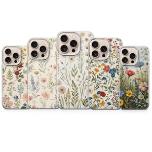 Puede incluir: Cinco fundas para teléfono con diseños florales. Cada funda presenta una disposición diferente de flores en varios colores, incluyendo rojo, azul, amarillo y rosa, sobre un fondo blanco o crema. Las fundas tienen un borde transparente.