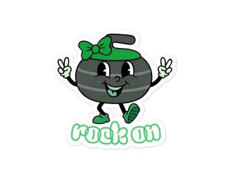 May include: A sticker featuring a cartoon curling stone with a green bow and hat. The stone has a smiling face and is giving the peace sign with both hands. The words "rock on" are written in green below the stone.