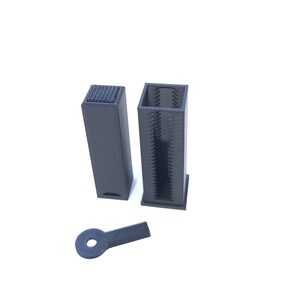 May include: Three black 3D-printed objects on a white background. There are two rectangular, hollow, vertical structures, one with a textured top. A small, flat, key-shaped object is also present.