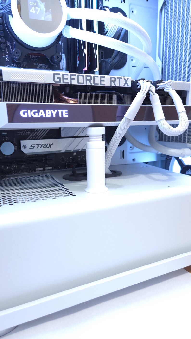 Peut inclure: Int&eacute;rieur d'un bo&icirc;tier d'ordinateur blanc avec une carte graphique portant les inscriptions "GEFORCE RTX" et "GIGABYTE". Des tubes blancs et un refroidisseur de processeur sont visibles. La temp&eacute;rature du processeur est affich&eacute;e &agrave; 47 degr&eacute;s.