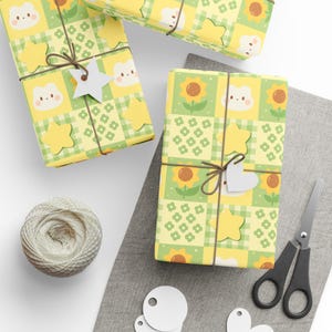 May include: Gift-wrapped presents with yellow and green patterned paper featuring sunflowers, stars, and cute animal faces. Each package is tied with brown twine and a white tag. A spool of twine and scissors are also visible.