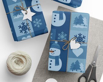 May include: Two rectangular gifts wrapped in blue paper featuring a repeating pattern of snowmen, snowflakes, hearts, and pine trees. Each gift is tied with brown twine and adorned with a white paper tag. A ball of twine and scissors are present.