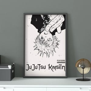 May include: Black and white framed poster featuring an anime character with spiky hair and a hand above their head. The poster has the text "Jujutsu Kaisen" in a stylized font. The poster is displayed on a white shelf.