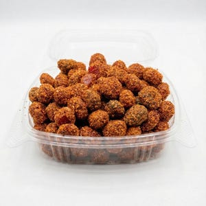 May include: A clear plastic container filled with a generous portion of brown, spherical candies. The candies are coated in a reddish-brown powder, giving them a textured appearance. The container is open, revealing the contents.