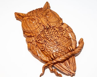 May include: A wooden owl wall sculpture with intricate carvings and a detailed design. The owl is carved in a light brown wood and has a realistic appearance.