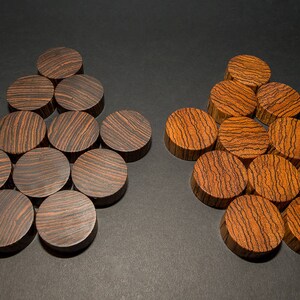 May include: Two sets of wooden game pieces, each arranged in a star-like pattern. One set is dark brown with black grain, the other is a lighter brown with darker grain. The pieces are circular and appear to be made of wood.