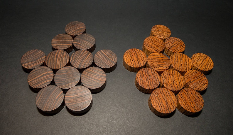 May include: Two sets of wooden game pieces, each arranged in a star-like pattern. One set is dark brown with black grain, the other is a lighter brown with darker grain. The pieces are circular and appear to be made of wood.