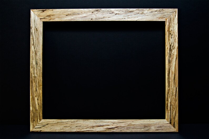 Op de afbeelding: Een natuurlijk houten fotolijst met een lichtbruin en donkerbruin houtnerfpatroon. De lijst is rechthoekig en heeft een eenvoudig ontwerp.