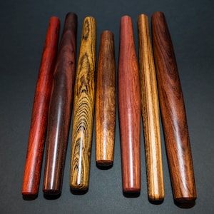 May include: Seven wooden rolling pins of varying lengths and colors. The rolling pins are made of different types of wood, including maple, cherry, and walnut. The rolling pins are all smooth and polished.