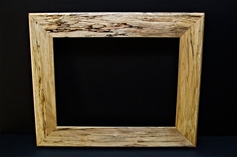 Op de afbeelding: Een fotolijst van natuurlijk hout met een rustieke, knoestige afwerking. De lijst heeft een brede, rechthoekige vorm en een eenvoudig, ongekleed ontwerp.