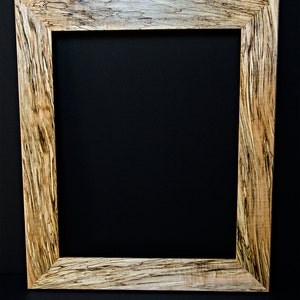 Op de afbeelding: Een houten fotolijst met een natuurlijke houten afwerking en een uniek houtnerfpatroon. De lijst is gemaakt van lichtbruin hout met donkerbruine strepen.