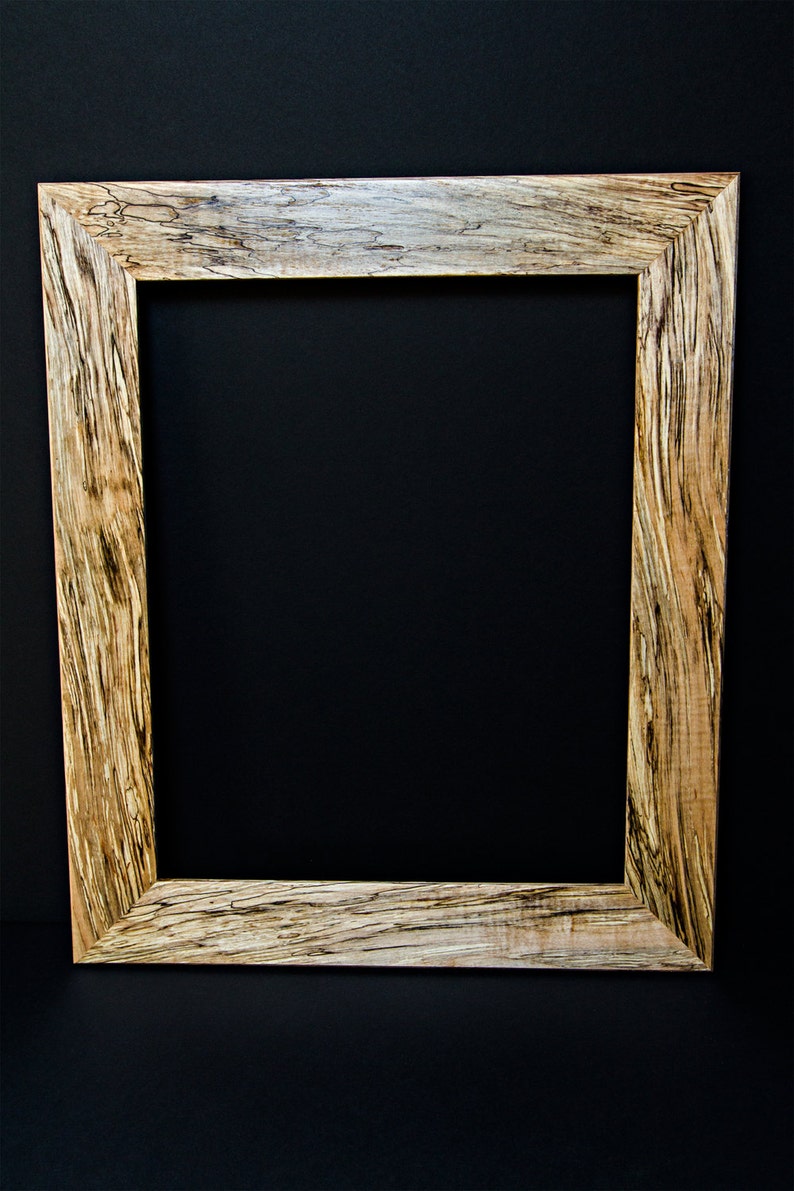 Op de afbeelding: Een houten fotolijst met een natuurlijke houten afwerking en een uniek houtnerfpatroon. De lijst is gemaakt van lichtbruin hout met donkerbruine strepen.