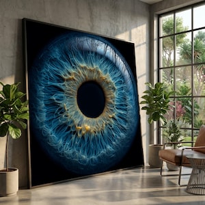 Puede incluir: Gran impresión enmarcada de un ojo humano, que muestra los intrincados detalles del iris y la pupila. El iris es de un azul vibrante con acentos dorados, sobre un fondo negro. La obra de arte se exhibe en un entorno interior moderno.