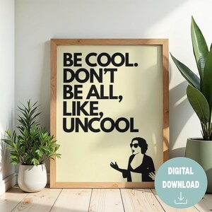 Puede incluir: Una impresión enmarcada con el texto "BE COOL. DON'T BE ALL, LIKE, UNCOOL" en letras negras en negrita. La impresión tiene un fondo amarillo claro y una silueta de una persona con gafas de sol. Un icono de descarga digital está en la parte inferior derecha.