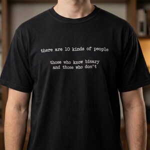 May include: Black crew neck t-shirt with white text: "there are 10 kinds of people, those who know binary and those who don't." The shirt is made of a soft material, likely cotton.