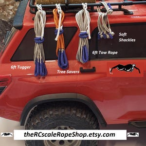 May include: A red vehicle displays various rope accessories, including a 6ft Tugger, Tree Savers, a 6ft Tow Rope, and Soft Shackles. The ropes are in bundles with blue and orange accents. The text "theRCscaleRopeShop.etsy.com" is visible.