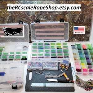 May include: Clear plastic storage containers filled with various colored cords, wires, and small parts. A black cutting board with tools and a ruler is in the foreground. The text "theRCscaleRopeShop.etsy.com" is at the top.