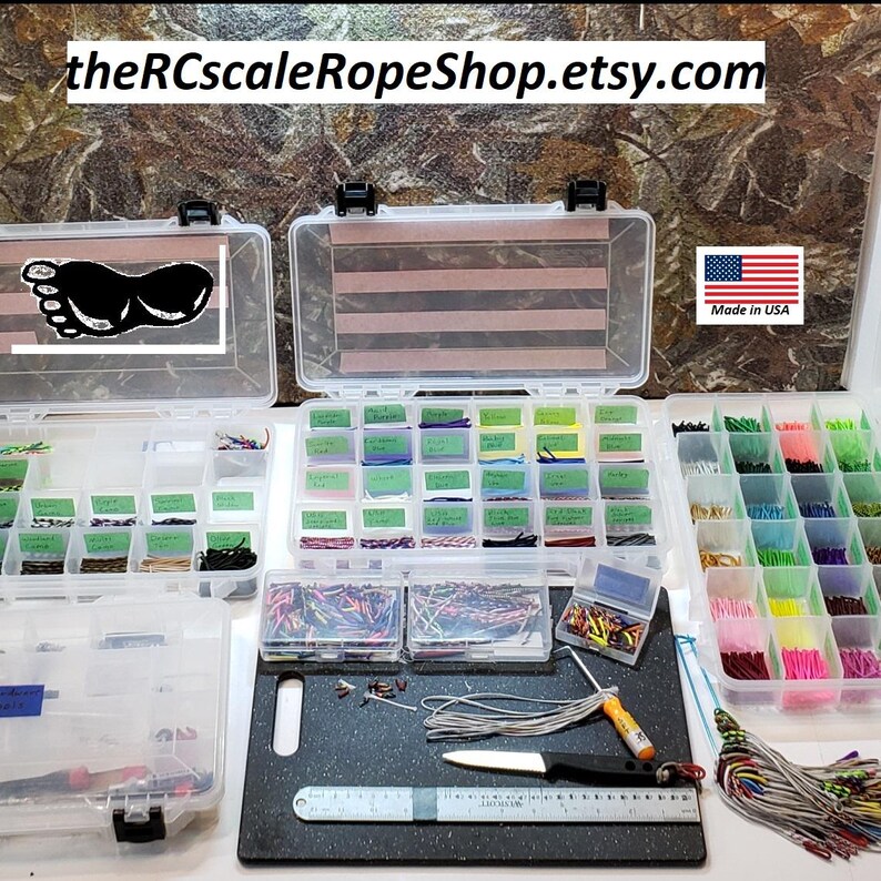 May include: Clear plastic storage containers filled with various colored cords, wires, and small parts. A black cutting board with tools and a ruler is in the foreground. The text "theRCscaleRopeShop.etsy.com" is at the top.