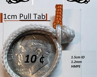 Puede incluir: Un grillete blando con una lengüeta de tracción de 1 cm, con una moneda de plata con "10¢" impresa. El grillete está hecho de cuerda blanca y tiene un acento naranja. También es visible el texto "1,5 cm ID" y "1,2 mm HMPE".