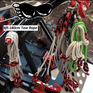 Puede incluir: Un conjunto de cuerdas de remolque en varios colores, incluyendo gris, verde y blanco, con detalles en rojo y negro. La imagen muestra una cuerda de remolque de 180 cm, con el texto "6ft-180cm Tow Rope".