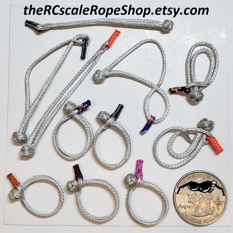 May include: A collection of miniature gray ropes and loops with colorful accents. Some ropes are tied into knots, while others form simple loops. The text "theRCscaleRopeShop.etsy.com" is visible at the top of the image.