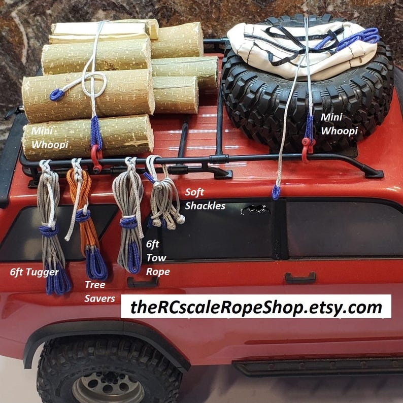 Puede incluir: Un cami&oacute;n de juguete rojo con una llanta negra, cuerdas y troncos de madera en la parte superior. La imagen incluye el texto "Mini Whoopi", "Soft Shackles", "6ft Tugger", "Tree Savers", "6ft Tow Rope" y "theRCscaleRopeShop.etsy.com".
