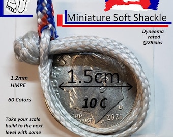 Puede incluir: Un grillete blando en miniatura hecho de cuerda HMPE de 1,2 mm, que se muestra alrededor de una moneda de 10 céntimos para comparar el tamaño. El grillete está clasificado para 285 libras y tiene 1,5 cm de diámetro. El texto de la imagen dice "Miniature Soft Shackle" y "60 Colors".