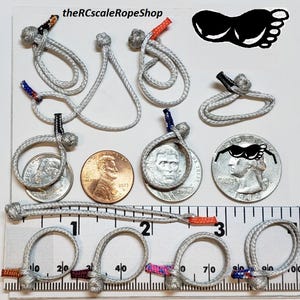 May include: A collection of small, gray rope loops and knots, some with colored accents, are displayed with US coins and a ruler. The text "theRCscaleRopeShop" is visible at the top. The image includes a black footprint graphic.