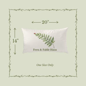 May include: A white rectangular pillow with a fern and ladybug design. The pillow is 20 inches long and 14 inches wide. The text "Fern & Fable Haus" is printed on the pillow. The words "One Size Only" are also printed on the image.