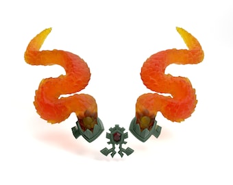 May include: A pair of orange and yellow dragon tail-shaped ornaments with green bases and a red gem in the center.