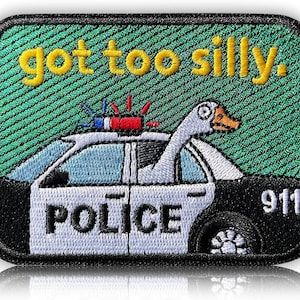 May include: Embroidered patch featuring a police car with a goose sticking its head out the window. The text "got too silly" is embroidered in yellow above the car. The car has a red and blue light bar and the number 911.