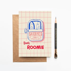 May include: Greeting card with a sardine can illustration in blue and pink, the words "Sardines" and "Best Roomie" are printed on the card. A brown envelope and a pencil are next to the card.