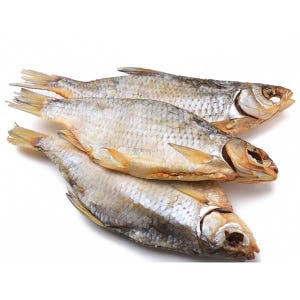 May include: Four dried fish are stacked on a white surface. The fish have silver scales, with yellow and brown fins and tails. The fish are arranged diagonally, with their heads facing right.