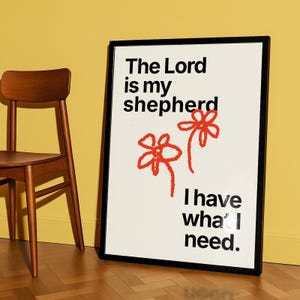 May include: A framed art print with the text "The Lord is my shepherd, I have what I need." The print features two red flower illustrations. A wooden chair is visible to the left of the print.