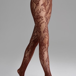 May include: Brown floral patterned tights. The tights feature a delicate, intricate floral design that covers the entire leg. The color is a deep, rich brown, and the material appears to be sheer. The tights are designed to be worn on the legs.