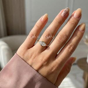 Minimalist marquise ring on finger, women's bypass engagement ring true to size, elegant hand model shot.