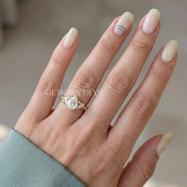 14k gold bridal jewelry set featuring a pear-shaped engagement ring with a dainty botanical leaf wedding band style