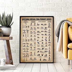 May include: A framed poster displays the Ashtanga Vinyasa Yoga Primary Series. The poster features illustrations of yoga poses in a grid format, with text labels. The frame is black, and the background is a neutral beige color.