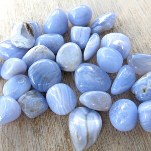 May include: A collection of blue agate tumbled stones. The stones are smooth and polished, with a variety of blue and white patterns.