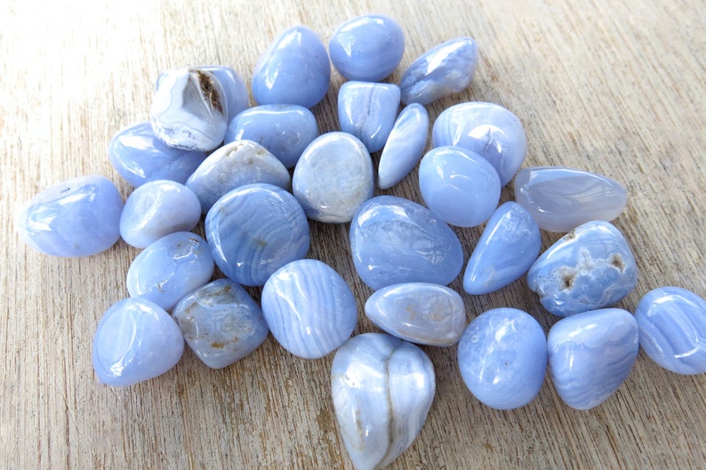 May include: A collection of blue agate tumbled stones. The stones are smooth and polished, with a variety of blue and white patterns.