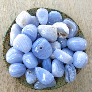 May include: A bowl filled with blue agate tumbled stones. The stones are smooth and polished, with a variety of blue and white patterns.