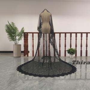 May include: A black bridal veil with a lace trim, displayed on a mannequin. The veil is long, with a rounded, scalloped edge. The word "Thirawit" is visible in the image.